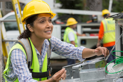 Hispanic female utility worker working with line amplifiers at site photo