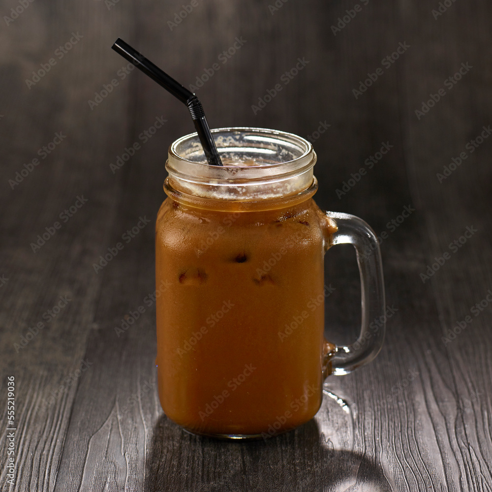 Iced Coffee with straw served in mug isolated on table side view healthy morning drink Iced Coffee with straw served in mug isolated on table side view healthy morning drink