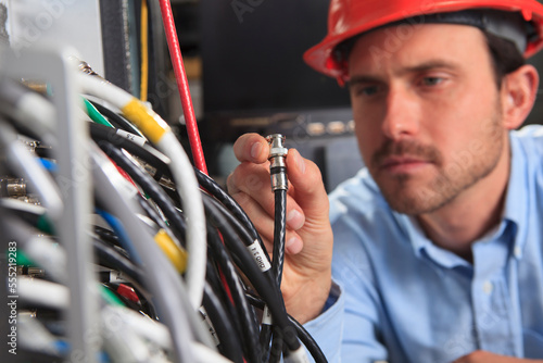 Network engineer holding BNC cable connection at patch panel photo