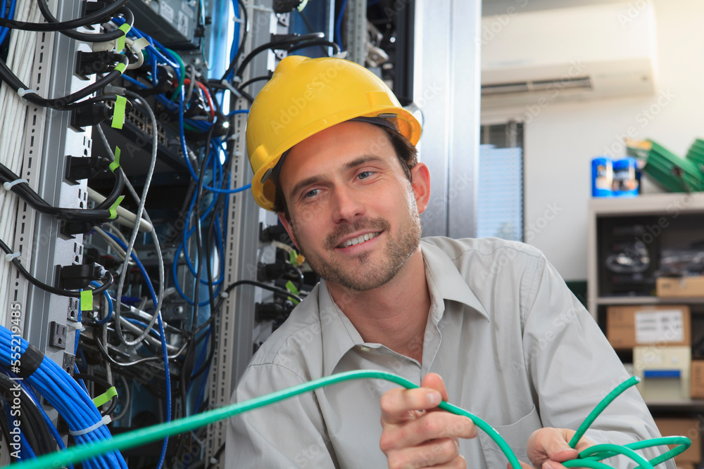 Network engineer pulling cable from reel in network data center Stock