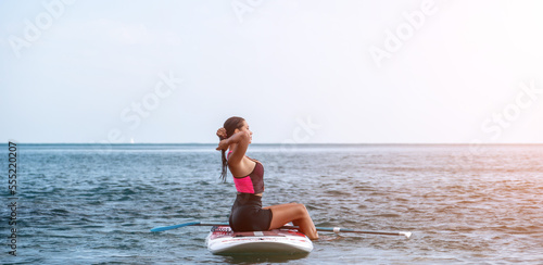 Sea woman sup. Silhouette of happy young woman in pink bikini, surfing on SUP board, confident paddling through water surface. Idyllic sunset. Active lifestyle at sea or river © panophotograph