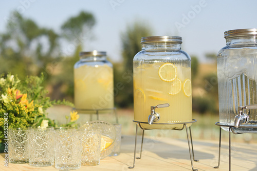 Natural lemonade dispenser with outdoor vintage glass cups photo