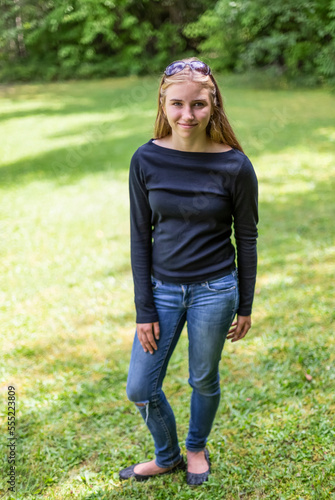 Portrait of a pre-teen girl standing on grass in a  park; Salmon Arm, British Columbia, Canada photo