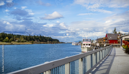 Boats in the harbour and walkway to colourful buildings on the waterfront of La Conner, a town on the coast of the Pacific Northwest; La Conner, Washington, United States of America photo