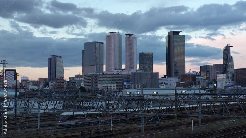 NAGOYA, JAPAN - OCT 2022 : View of buildings around NAGOYA STATION and railroad in sunset from Koyabashi (bridge). Time lapse shot, dusk to night. Japanese business and transportation concept video.