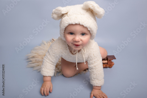 One year birthday party decorations. Little boy in bear costume of a blue wall. Happy child playing with glowing letters one. blue background. cute baby in bear costume playing with wooden toy