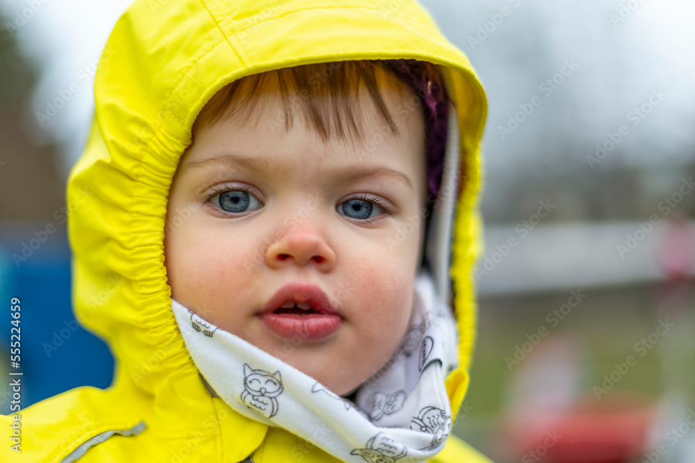 Cute toddler girl with blue eyes wearing bright yellow raincoat; North Vancouver, British Columbia, Canada Cute toddler girl with blue eyes wearing bright yellow raincoat; North Vancouver, British Columbia, Canada