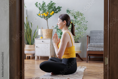 woman in yellow top does yoga and meditation at home on mat. lady is engaged in physical exercises and breathing practices for health of body and mentality. stretching and spiritual exercises