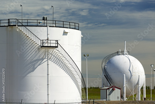 Close up of two large white oil storage tank with black metal stairs with shadows and blue sky and clouds, North of Longview; Alberta, Canada photo