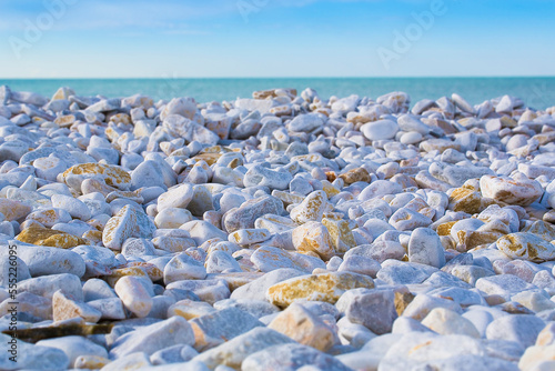 White and gray stones softly rounded and washed from sea water with horizon over the sea