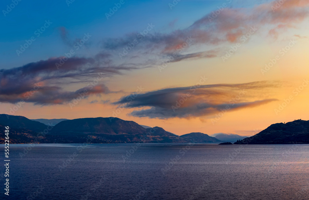 Golden sunset light glowing in the sky over Okanagan Lake and mountain range; British Columbia, Canada Golden sunset light glowing in the sky over Okanagan Lake and mountain range; British Columbia, Canada