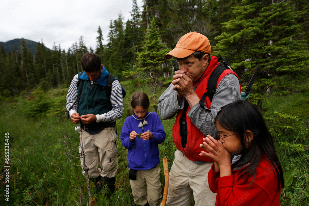 Conservationists with their daughters whistle using blades of grass