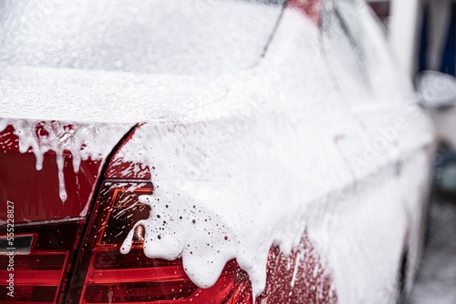 Obraz na płótnie red car covered with white active foam at a manual car wash w salonie