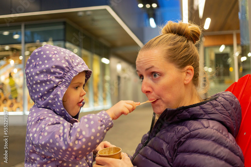 Mother and young daughter share a snack at Lonsdale Quay, North Vancouver; North Vancouver, British Columbia, Canada photo