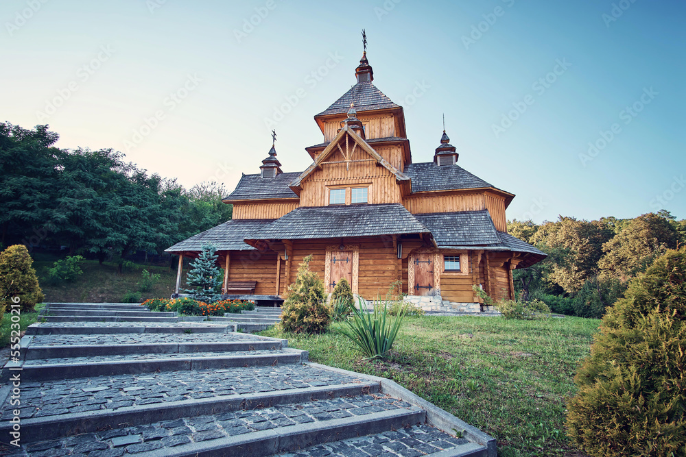 Ukraine. A wooden church in the middle of the park. A beautiful cobblestone road leads to it.