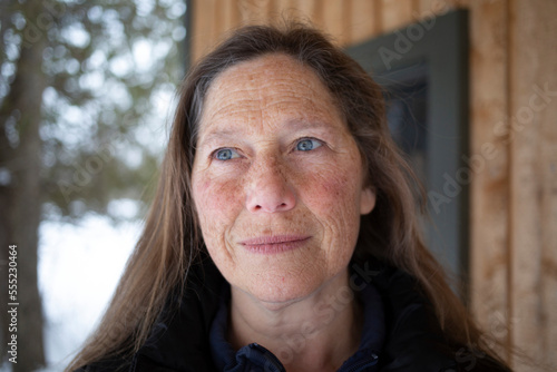 Portrait of a mature woman standing outdoors with a freckled face and blue eyes looking upwards; Ottawa Valley, Ontario, Canada photo
