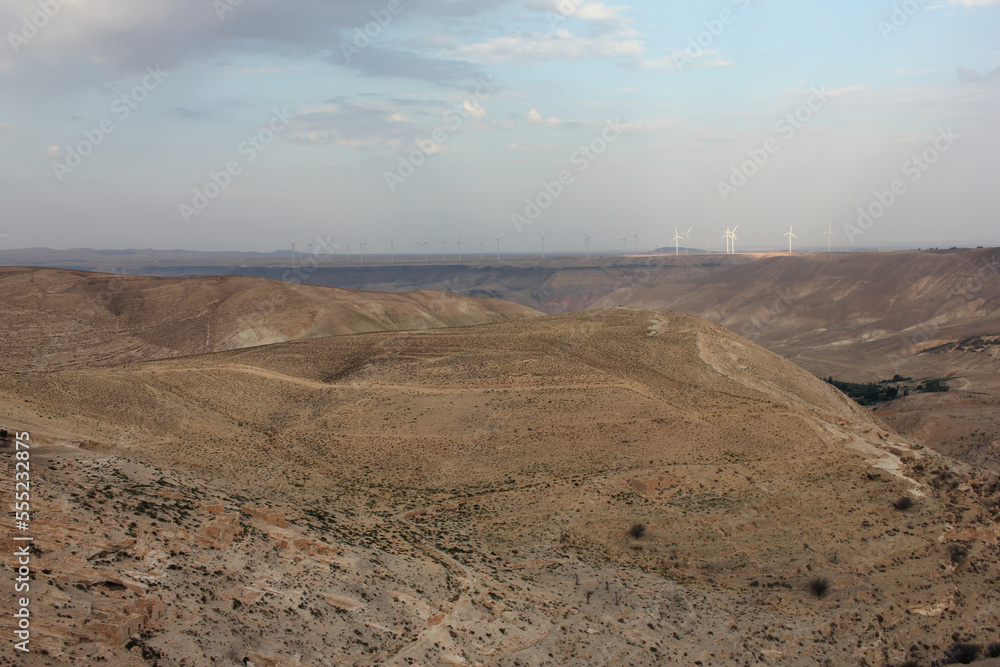 Desert landscape view of sunny rocky cliff with wind turbines in view taken from Shobak Castle, Jordan