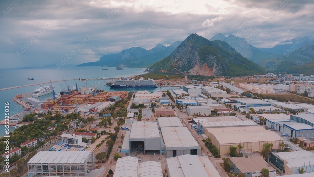 Aerial drone view of storage facilities of the cargo port on the seashore. Mountains in the background