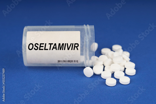 On a blue surface are pills and a dusty jar with the inscription - Oseltamivir photo