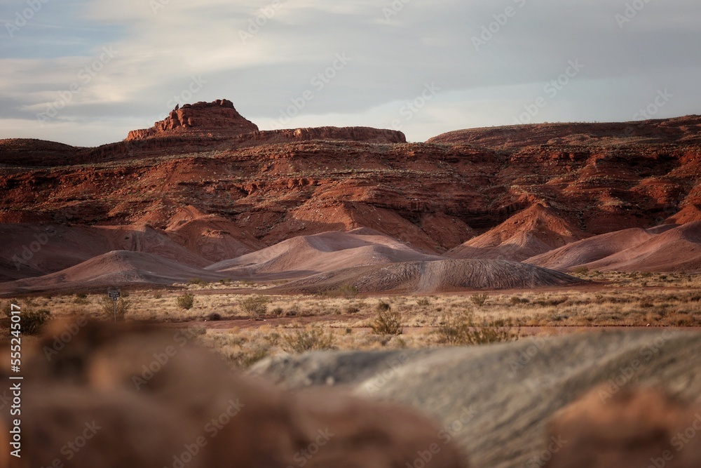 Red desert landscape with layers of color and sand in foreground