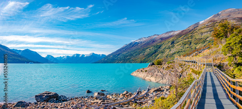 Panoramic view over blue sky and turquoise water glacial lagoon near Perito Moreno glacier in Patagonia with a modern metal walking path for tourists, South America, Argentina, in Autumn colors photo