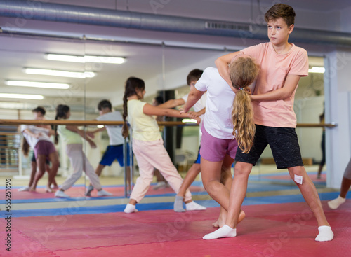Preteen children working in pair mastering new self-defense moves at gym