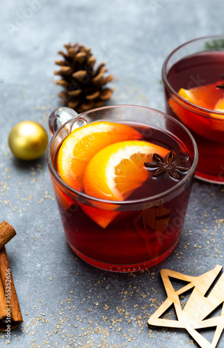 Two cups of christmas mulled wine or gluhwein with spices and orange slices on rustic table top view.