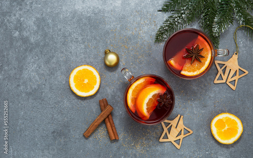 Two cups of christmas mulled wine or gluhwein with spices and orange slices on rustic table top view.
