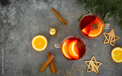 Two cups of christmas mulled wine or gluhwein with spices and orange slices on rustic table top view. 