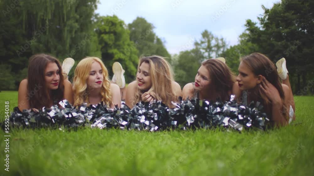 Portrait of happy cheerleading team lying on grass and talking. Realtime Portrait of happy cheerleading team lying on grass and talking. Realtime