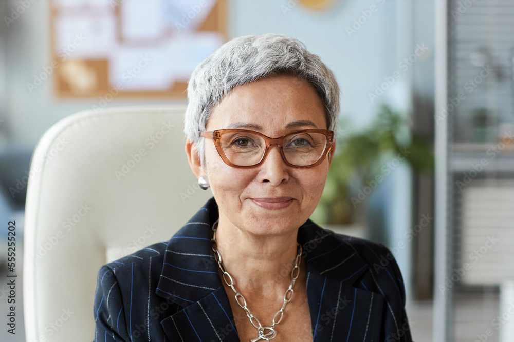 Portrait of senior woman as female boss sitting at workplace and smiling at camera Portrait of senior woman as female boss sitting at workplace and smiling at camera