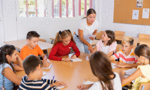 Canvas Print Positive young female teacher giving lesson for group of preteen schoolchildren