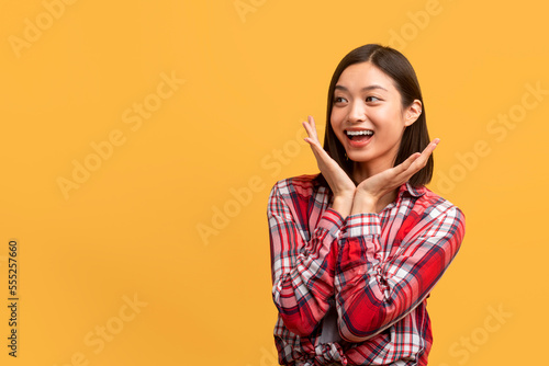 Huge sale or promo concept. Joyful korean woman screaming and touching her cheeks, looking at copy space