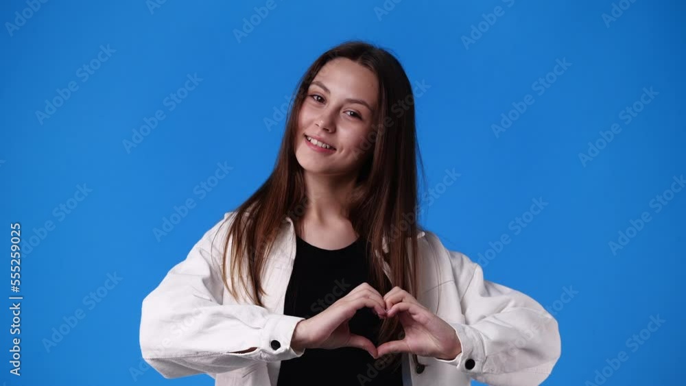4k slow motion video of girl making heart shape with her hands on blue backround. 4k slow motion video of girl making heart shape with her hands on blue backround.