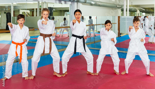 Female trainer is training young teenagers in karate class