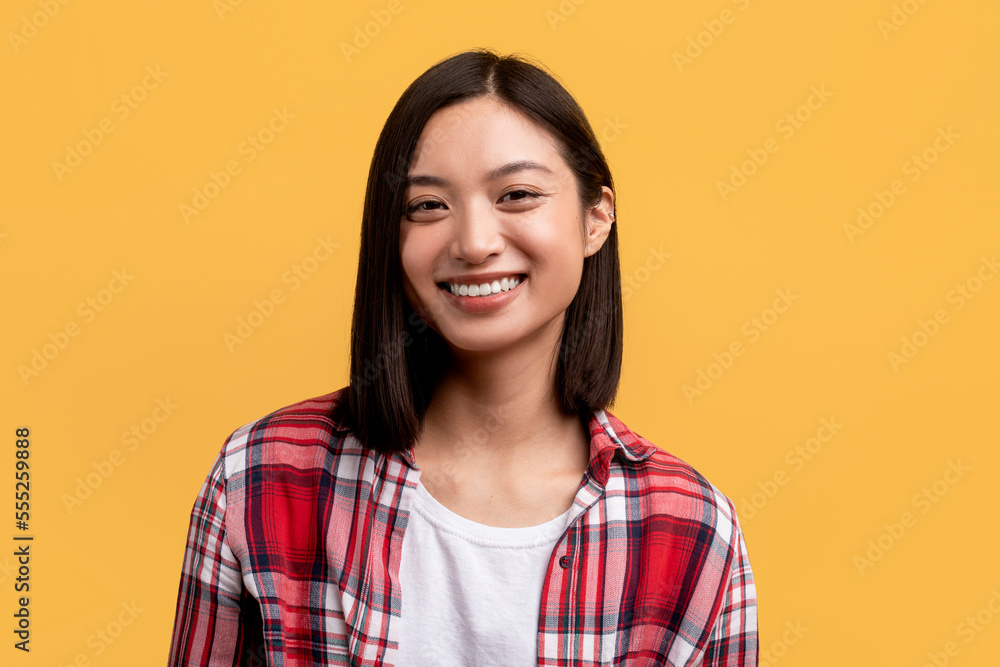 Happy person. Portrait of young asian lady with beautiful smile, looking at camera, posing in studio, yellow background Happy person. Portrait of young asian lady with beautiful smile, looking at camera, posing in studio, yellow background