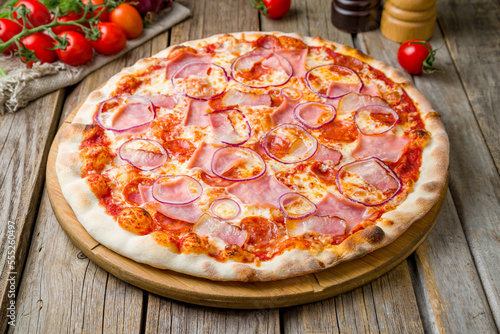 Italian meat pizza with cheese and tomato sauce on wooden table close up