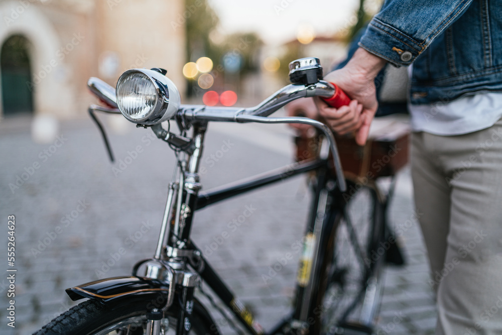 Unrecognizable young man in denim jacket holding his vintage classic bike. Unrecognizable young man in denim jacket holding his vintage classic bike.