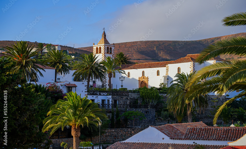 Panoramic wide view of the church of Saint Mary of Betancuria surrounded by palm trees at sunset in the former capital city of Fuerteventura island in the Canaries, Spain