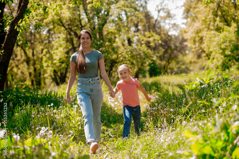 Fototapeta premium Young woman and her daughter walking in the forest