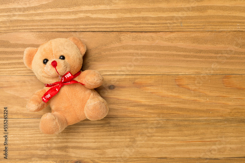 Cute teddy bear on wooden background, top view