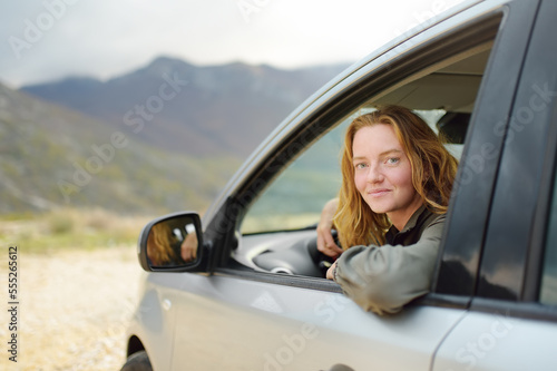 A young beautiful red-haired woman travels alone driving her car.