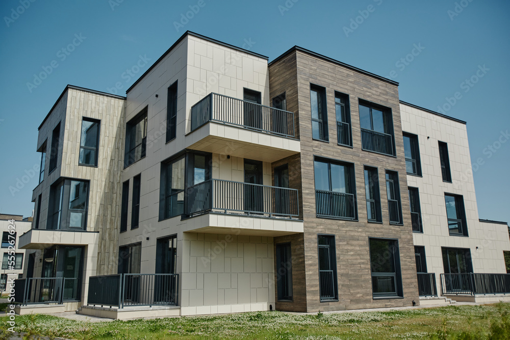 Wide angle shot of modern apartment building in housing complex lit by sunlight