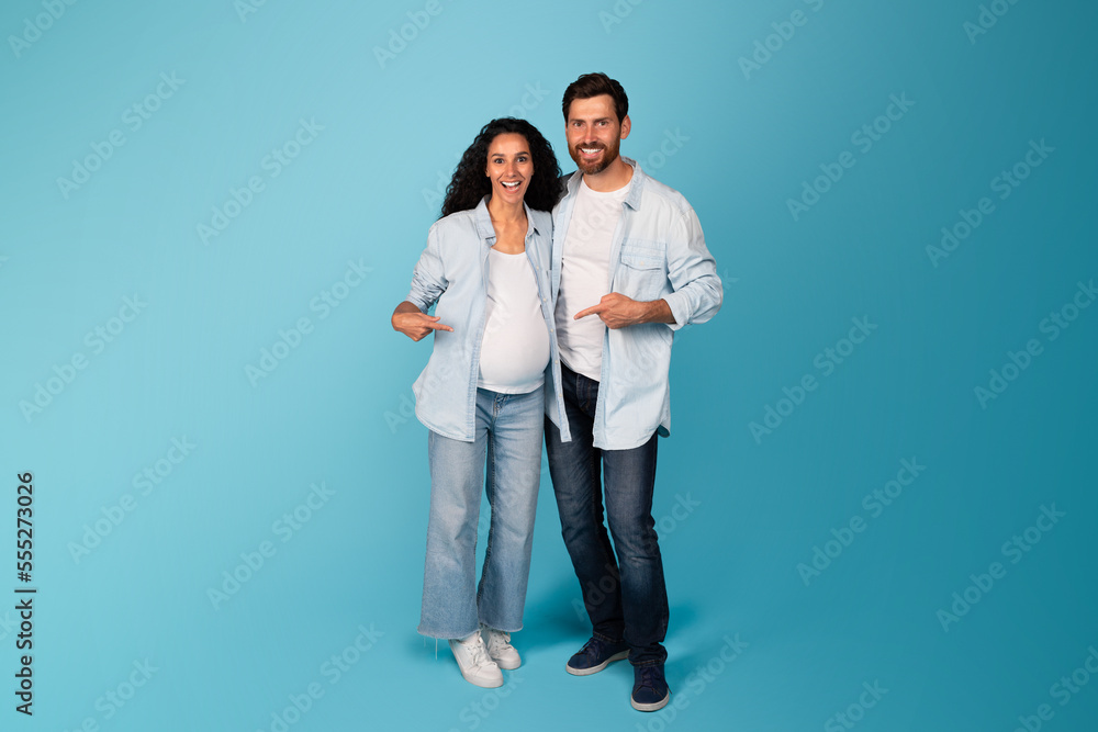 Glad young european guy and pregnant lady in casual have fun together, show fingers on belly Glad young european guy and pregnant lady in casual have fun together, show fingers on belly