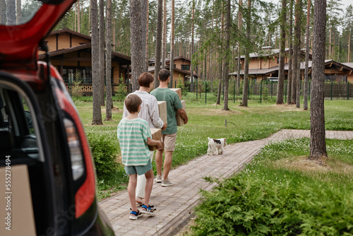 Wallpaper Mural Back view of family unloading boxes from car trunk while moving into new house in nature Torontodigital.ca