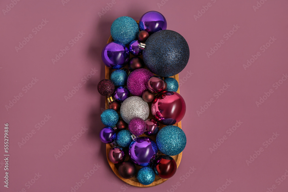 Wooden board with beautiful Christmas balls on color background Wooden board with beautiful Christmas balls on color background