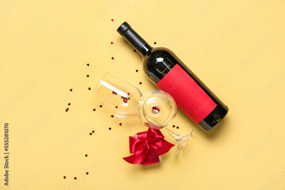 Bottle of wine, glasses and gift on yellow background. Valentine's Day celebration Bottle of wine, glasses and gift on yellow background. Valentine's Day celebration