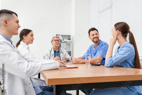 Medical conference. Team of doctors having discussion at wooden table in clinic
