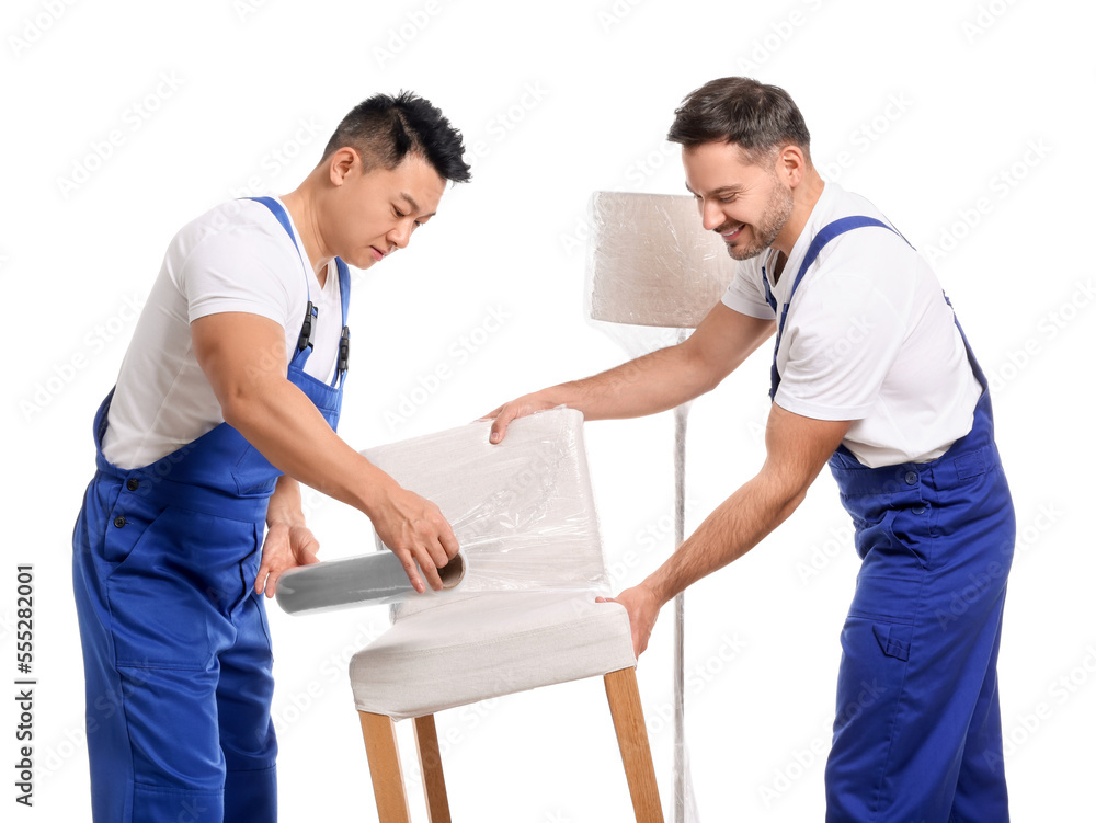 Fototapeta premium Workers wrapping chair in stretch film on white background