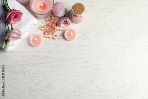 Flat lay composition with burning candles and different spa products on white wooden table. Space for text